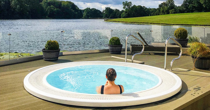 woman sat in outdoor hot tub overlooking lake at Wynyard Hall hotel's spa.